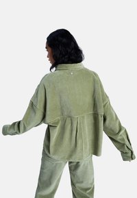 Φαρδιά μπουφάν από κορντόρι σε αποχρώσεις απαλού πράσινου, με γιακά, ριμπ υφή και κουμπί στη πλάτη.