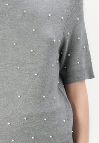 Gray knit sweater with short sleeves, featuring scattered pearl accents and a soft texture. Crew neckline and ribbed cuffs.