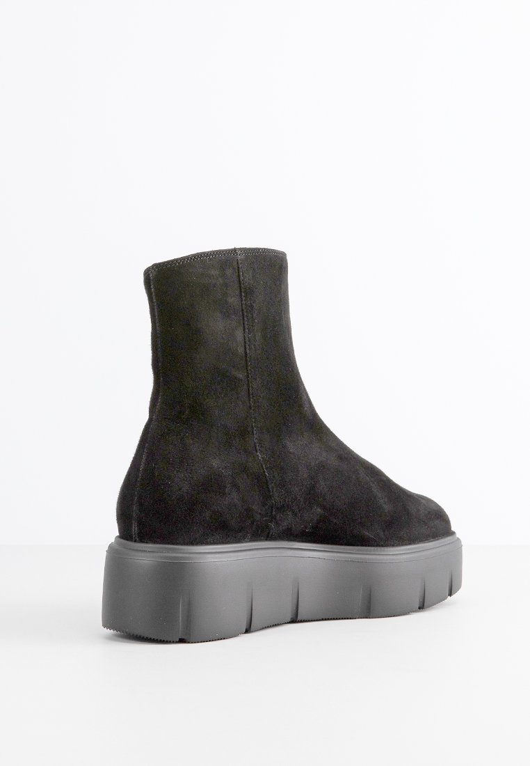 Stivaletti in suede neri con un design elegante, una spessa suola piatta grigia e cuciture minimaliste lungo le cuciture.