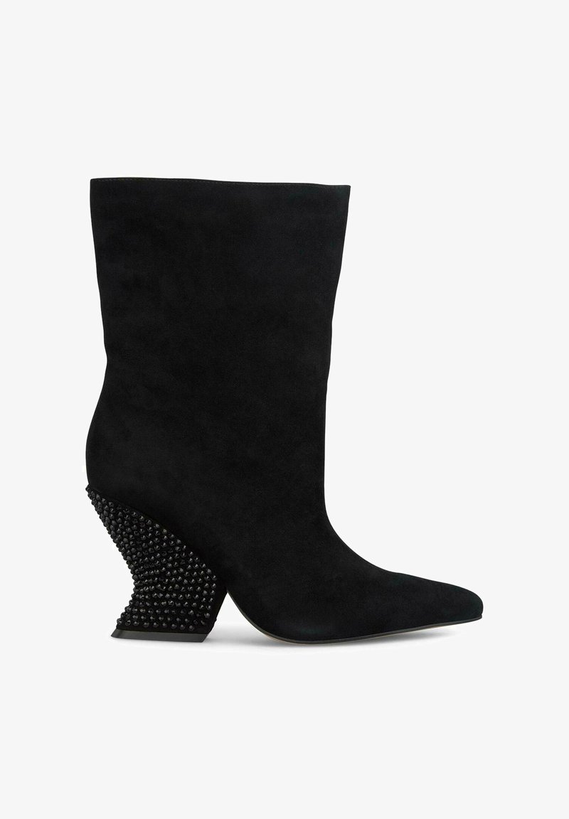Zwarte suède enkelboot met een puntige neus, voorzien van een opvallende getextureerde zwarte studs-wedge hak.