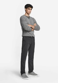 Grau pullover mit rundem Halsauschnitt, schwarze Hose und graue Sneaker. Der Stoff wirkt weich mit glatter Textur und hat ein einfaches Design.