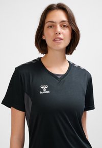 Czarny sportowy T-shirt z dekoltem w serek, krótkimi rękawami, szarymi akcentami na ramionach oraz białym logo na piersi.