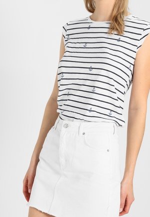 Wit gestreept hemdje met blauwe ankerprints, gecombineerd met een witte denim rok. Het hemdje heeft een mouwloos ontwerp en een losse pasvorm.