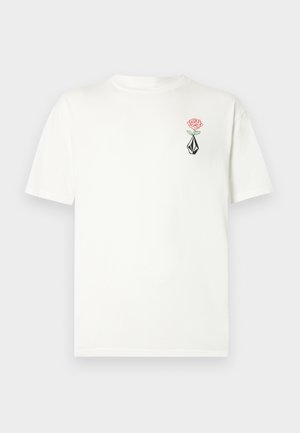 T-shirt en coton blanc à manches courtes. Présente une rose rose et un motif géométrique noir brodé sur la poitrine gauche.