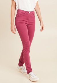 Roze skinny jeans van een katoenmengsel, met een klassiek vijf-pocket ontwerp, frontale knoopsluiting en subtiele stikdetails, gecombineerd met witte sneakers.