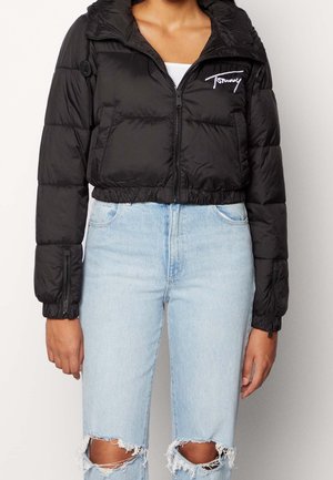 Veste matelassée noire avec un design court, matériau brillant, fermeture éclair à l'avant, capuche et poignets élastiques. Présente le logo Tommy sur la poitrine.