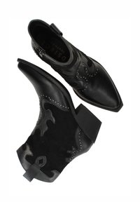 Zwarte enkelboots met een spitse neus, gemaakt van leer en suede, decoratieve stiksels en studaccenten aan de zijkanten.