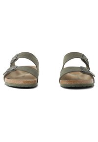 Green, two-strap sandals made of textured material, featuring silver buckles and a cork footbed. Flat rubber sole without patterns.