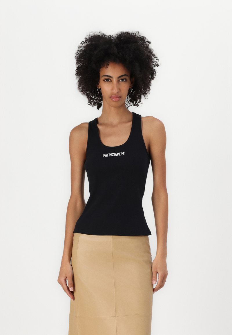 Melns ribots top ar izgriezumu, ar baltiem "PATRIZIA PEPE" uzrakstiem priekšā. Apvienots ar bēša taisnas griezuma svārkiem.