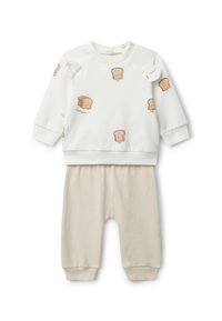 Sudadera blanca con estampados de pan de dibujos animados, con hombros redondeados y puños de canalé, combinada con pantalones de algodón beige que cuentan con una cinturilla elástica.