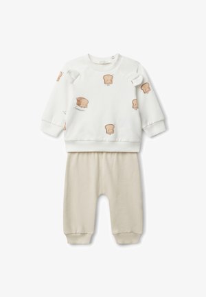 Sudadera blanca con estampados de pan de dibujos animados, con hombros redondeados y puños de canalé, combinada con pantalones de algodón beige que cuentan con una cinturilla elástica.