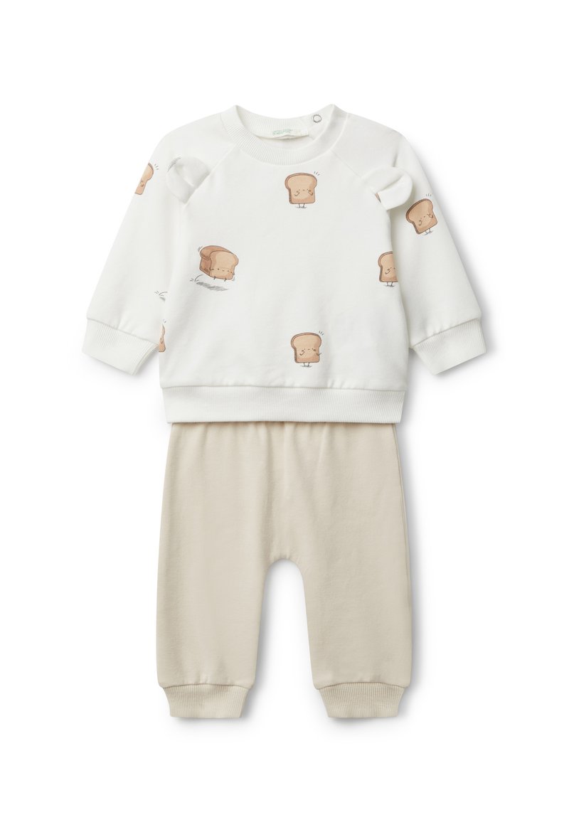 Sudadera blanca con estampados de pan de dibujos animados, con hombros redondeados y puños de canalé, combinada con pantalones de algodón beige que cuentan con una cinturilla elástica.
