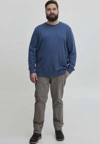 Sudadera azul de Manga Larga, Cuello Redondo, Ajuste Relajado. Pantalones beige, ligeramente sueltos, combinados con zapatos negros. Diseño simple y clásico.