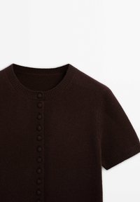 Brązowy kardigan z krótki rękawami, okrągłym dekoltem i zapięciem na guziki z małymi, okrągłymi guzikami po lewej stronie. Miękka faktura.