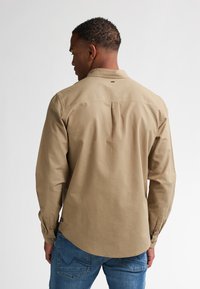 Lange mouw shirt van katoen, met een button-down kraag, rugplooi en knopenmanchetten, gecombineerd met blauwe denim jeans.