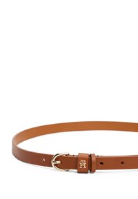 Bruine leren riem met een goudkleurige gesp en een eenvoudige leren houders. Het ontwerp is strak met minimale hardware en een geperst logo.