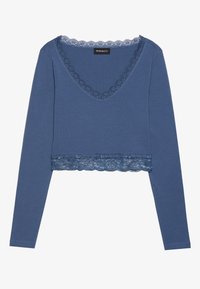 Blå langermet crop topp i mykt materiale, med V-hals dekorert med blonder og en blondekant nederst, som gir teksturerte detaljer.