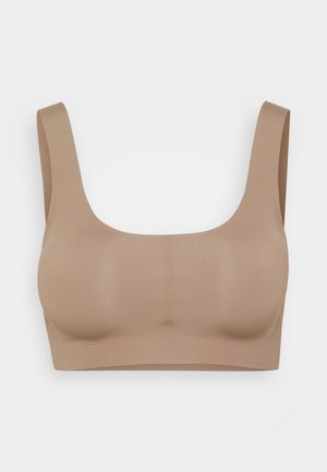 Beige seamless bra with a scoop neckline and wide straps. Smooth texture, no visible closures or padding. Simple, minimalist design.