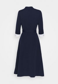 Navyblaues A-Linien-Kleid mit Dreiviertelärmeln, weißen Manschetten, taillierter Passform und einem Rückenreißverschluss. Glatte Stoffoberfläche.