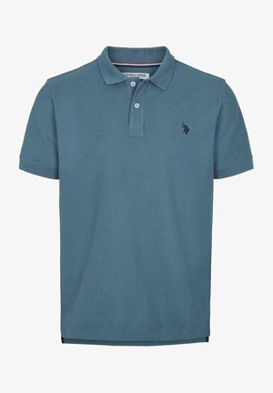 Polo en coton bleu clair avec une finition texturée, doté d'un col à deux boutons et d'un petit logo sombre sur la poitrine gauche.