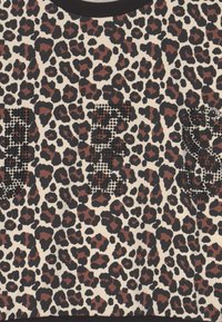 Kuningatikkakuvioinen kangas mustilla ja ruskeilla läiskillä, keskellä kohoavat mustat pistekirjaimet, jotka kirjoittavat "KYLLÄ".