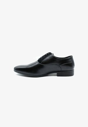 Chaussure de ville en cuir noir avec une finition lisse, bout pointu, coutures minimales et un petit talon carré. Présente un système de laçage.