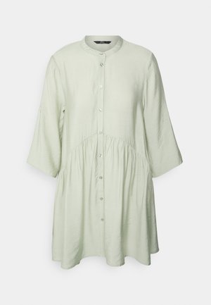 Camisa de botão de manga longa em verde claro, com gola redonda, cintura gather e um corte descontraído. Tecido suave com uma textura subtil.