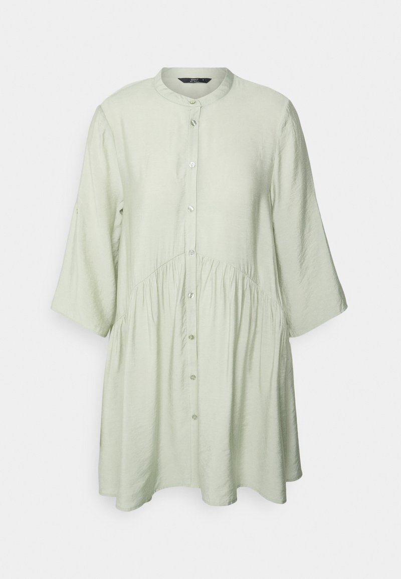 Camisa de botão de manga longa em verde claro, com gola redonda, cintura gather e um corte descontraído. Tecido suave com uma textura subtil.