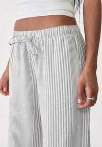 Gestreepte lichte broek in grijs en wit, met een elastische tailleband met trekkoord en een relaxte, wijde pasvorm.