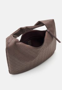 Brązowa pleciona torba na ramię o miękkiej fakturze, zaokrąglonym kształcie i zapięciu na zamek. Wnętrze wyłożone ciemniejszym materiałem, z eleganckim paskiem.