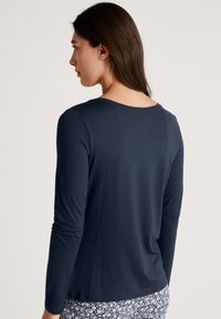 Marineblauwe longsleeve t-shirt met een ronde halslijn en een zachte, gladde textuur, gecombineerd met gestreepte broek in wit en marineblauw.