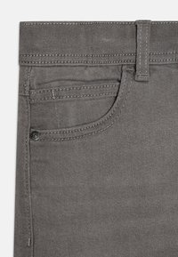 Jeans de mezclilla gris con una textura suave, que presentan un bolsillo frontal, un botón de metal y costuras contrastantes a lo largo de la cintura y las costuras.