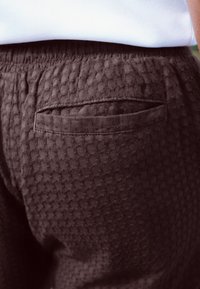 Czarne teksturowane szorty z podniesionym wzorem w kropki, elastycznym paskiem w talii i jedną tylną kieszenią.