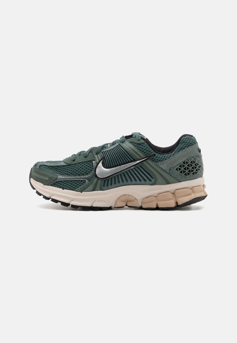Chaussure de course Nike en mesh vert foncé et synthétique avec un swoosh argenté et une semelle beige amortie vue de côté sur fond blanc.
