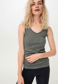 Grijze mouwloze top met een V-hals ontwerp, gemaakt van een zachte, gestructureerde stof. Aansluitend model met een subtiele plooidetail aan de onderkant.