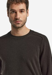 Ciemnoszara sweter wykonany na drutach, z okrągłym dekoltem i teksturowanym materiałem. Prosty fason, z luźnym krojem i prążkowanymi detalami przy kołnierzu.