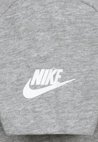 Γκρι φούτερ φτιαγμένο από μαλακό ύφασμα με λευκό λογότυπο και σχέδιο swoosh της Nike, με κλασική στρογγυλή λαιμόκοψη και υφή επιφάνειας.