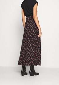Falda larga negra con estampado floral y cintura ajustada, confeccionada en tela suave. Presenta pequeños patrones de flores rosas sobre un fondo negro.