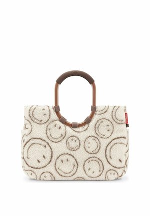 Sac cabas crème avec poignée ronde marron, recouvert de motifs de visages souriants marron sur un tissu doux et texturé.