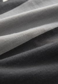 Cotton fabric in shades of gray, featuring a smooth texture with subtle ribbing. The material is draped, showing depth and layers.