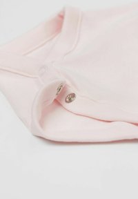 Jasnoróżowy bawełniany body z okrągłym dekoltem i zapięciem na napy na dole. Posiada prążkowaną strukturę na rękawach i u dołu.