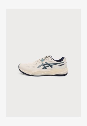 Basket de sport beige avec semelle, lacets et logo Asics bleu foncé, vue de côté sur un fond blanc uni.
