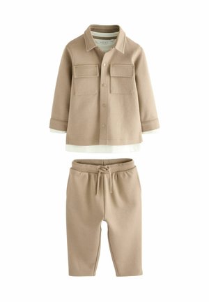 Ensemble beige en deux pièces comprenant une chemise à manches longues avec deux poches poitrine et un pantalon avec taille élastique assorti. Tissu doux et texturé.