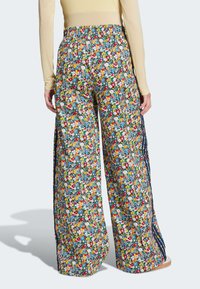 Floral wide-leg pants with a multicolored pattern on a dark blue background, featuring a smocked waistband and side slits.