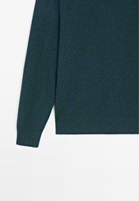 Tmavě zelený svetr s žebrovanou strukturou, dlouhými rukávy a rovnou spodní částí. Měkký materiál s jednoduchým, minimalistickým designem.