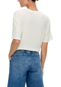 Witte T-shirt met korte mouwen, gemaakt van zachte stof, gecombineerd met lichtblauwe denim shorts met hoge taille, voorzien van achterzakken en zijnaad.