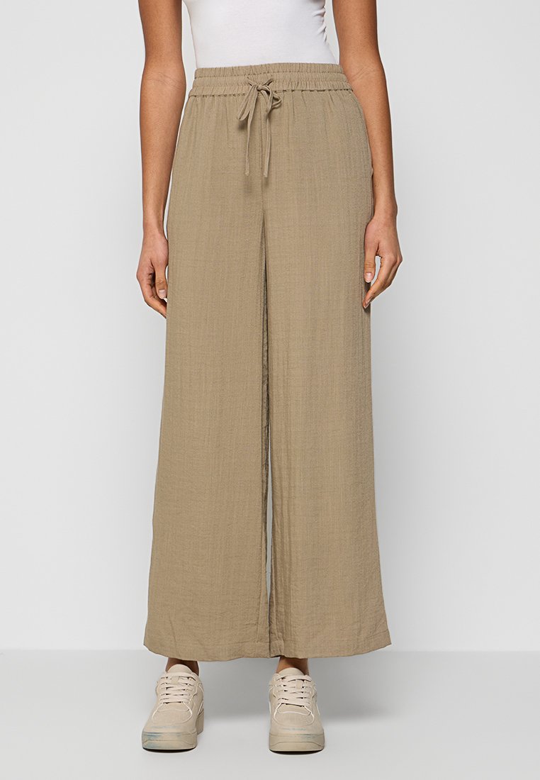 Beige weitem Bein Hosen aus leichtem Stoff mit strukturierter Oberfläche. Enthält einen elastischen Bund und einen verstellbaren Kordelzug für die Passform.