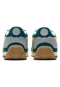 Sneakers with a layered design, featuring blue, yellow, and gray materials, a textured gum sole, and distinct circular accents on the heel.