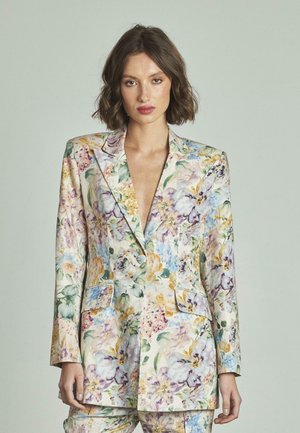 Blazer stampato floreale realizzato in un tessuto leggero e texture con colori vivaci. Elementi distintivi includono un profondo scollo a V e due tasche frontali.