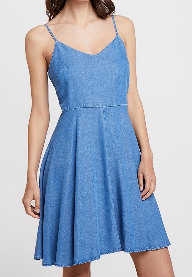 Jeansklänning med tunna band, V-ringning, figurnära midja och utsvängd A-linjekjol. Ljusblå färg med en något slitna fåll.